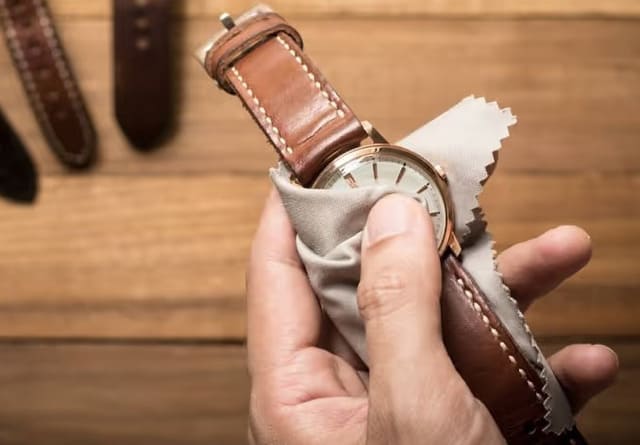 Người dùng đang lau dây da đồng hồ bằng khăn mềm để bảo quản sau khi sử dụng